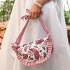 Person holding pink and white purse with peacock design