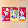 Three colorful red envelopes with cartoon character designs on a wooden surface