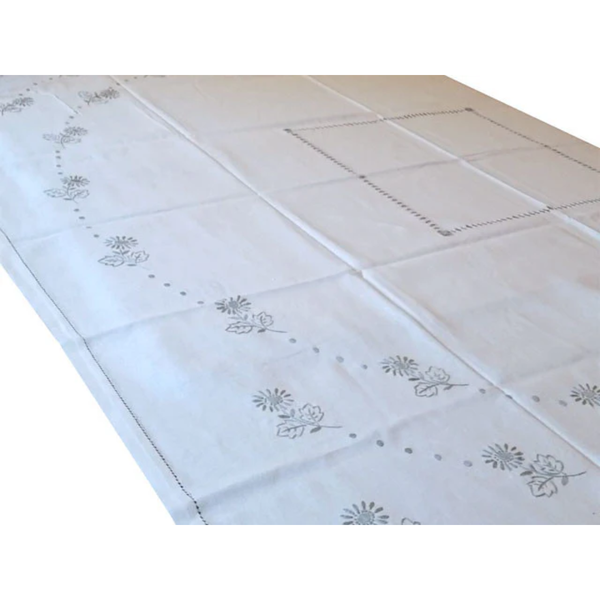 White tablecloth with floral embroidery on a tiled floor background