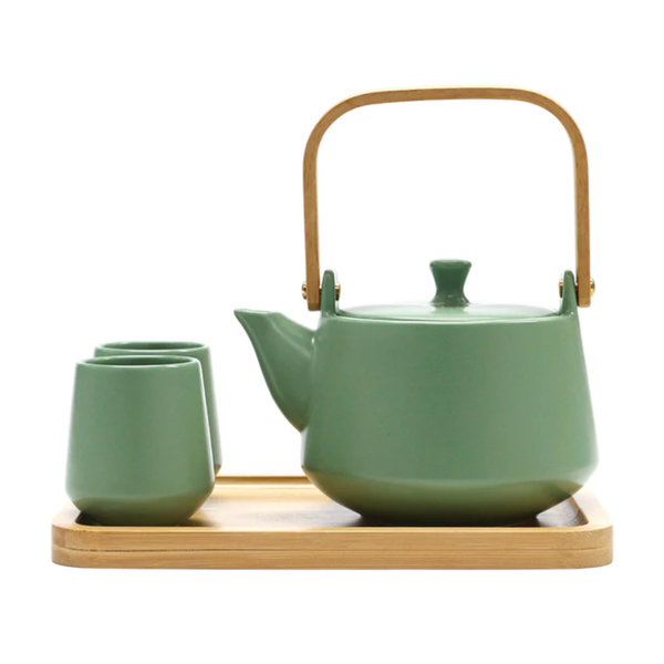 Green ceramic teapot with wooden handle and four matching cups on a wooden tray.