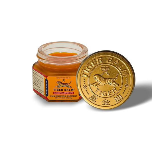 Tiger Balm ointment jar with its gold lid placed in front on a white background. The jar contains orange-colored balm and features the classic red and gold label with the tiger logo.