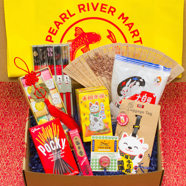 A gift box with Pearl River's favorite items including Pocky, lucky coin ornament, lucky cat, chopsticks, a fan, white rabbit candy, tiger balm, a cute luggage tag, and a 4-pack Bee & Flower soap