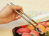 Travel chopsticks being used to pick up sushi