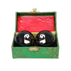 A pair of black cloisonne metal therapy balls, they have a panda painted on each ball. They are both in a green box