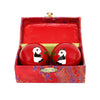 A pair of red cloisonné metal therapy balls with a panda painted on them. They are in a red box