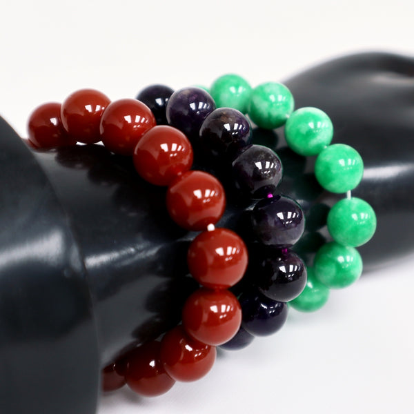 Three stone beaded bracelets. Each one in a different color: red, black and green