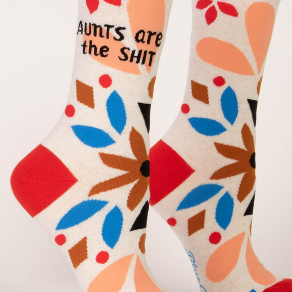 Aunts Are The Shit Novelty Socks: Beige socks with floral, nature-style pattern in brown, blue, black, and red with AUNTS ARE THE SHIT printed on it