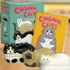 The chonks cats nesting dolls box, book and three cat dolls on a table