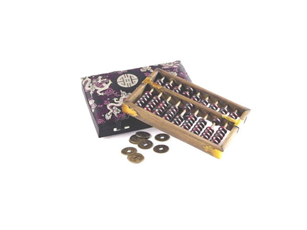 wooden abacus next to 7 coins and cushioned purple and white silk box