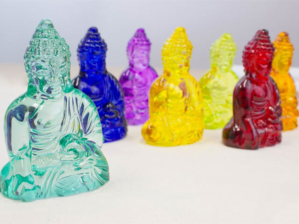 3.25" buddha crystal statues standing alongside one another. There is an orange, red, blue, purple, yellow, orange, light green, and teal