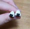 Hand holding pair of onigiri earrings