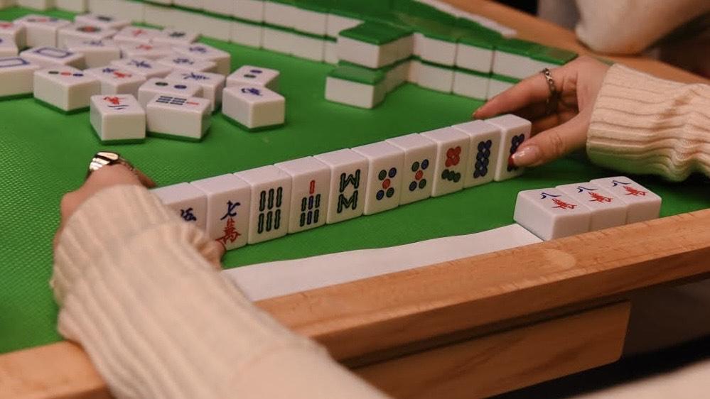 mahjong tiles with player hands on either side