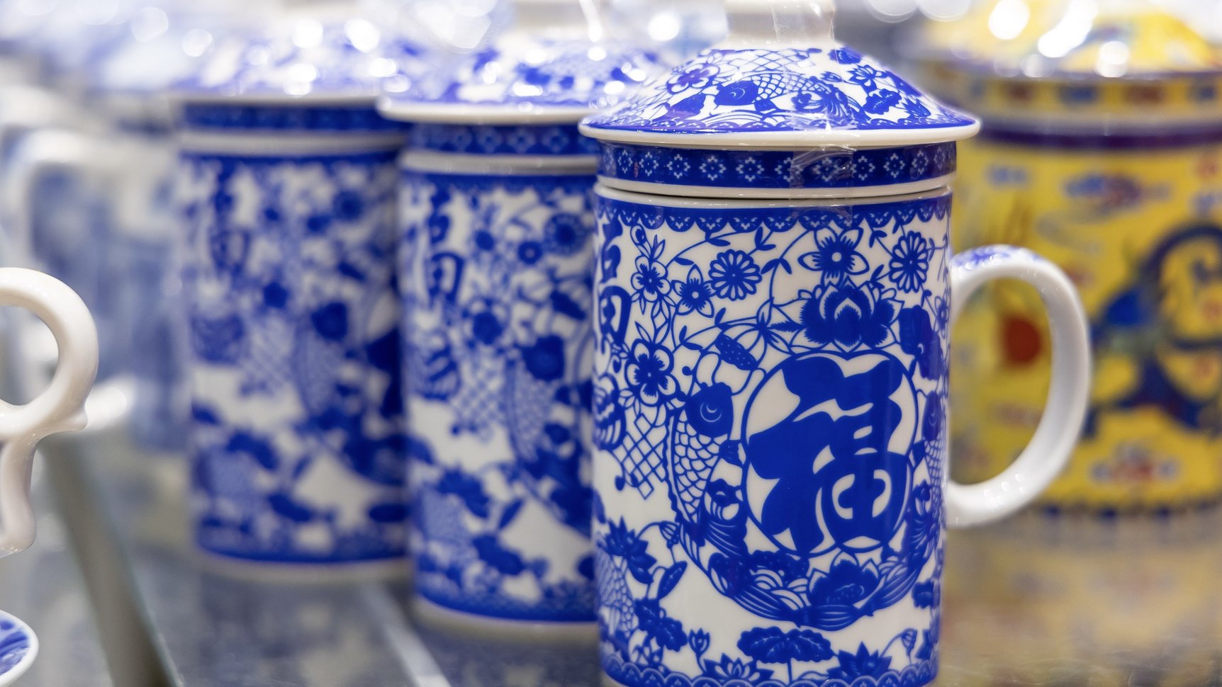 Three ceramic mugs with blue and white fu character and flower design